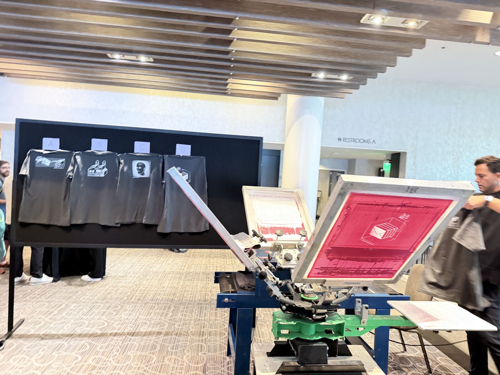 Attendees gathered at a professional Merch Troop event setup with screen printed shirts on display